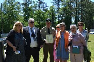 Group of people standing by officer holding plaque